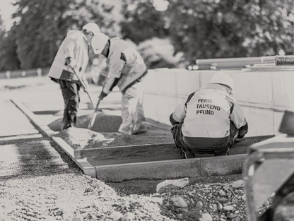 Bauarbeiter in Schutzkleidung und Helmen arbeiten an einer Baustelle.