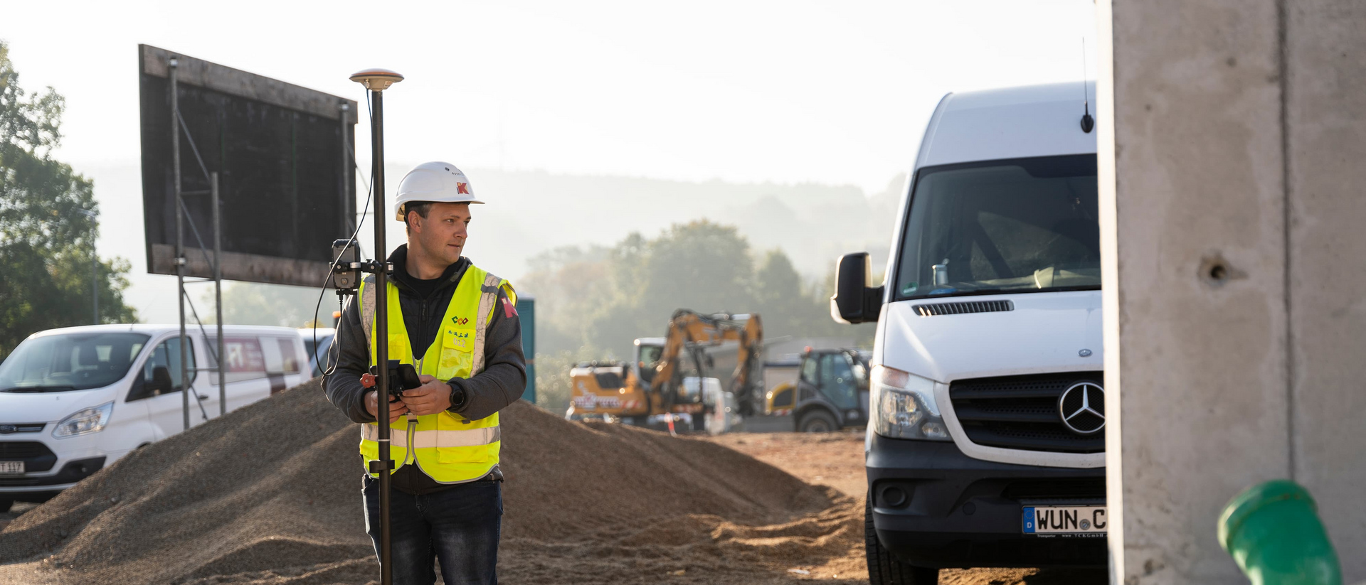 Mitarbeiter mit Vermessungsgerät auf Baustelle